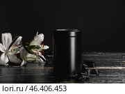 Mortuary urn with ribbon and lily flowers on table against dark background. Стоковое фото, фотограф Pixel_shot / Фотобанк Лори
