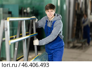 Guy glazer employee in blue overall works in glass processing shop. Стоковое фото, фотограф Яков Филимонов / Фотобанк Лори