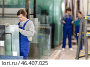 Man glazer employee in blue overall works in glass processing shop. Стоковое фото, фотограф Яков Филимонов / Фотобанк Лори