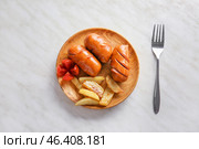 Plate with tasty grilled sausages and potatoes on light background. Стоковое фото, фотограф Pixel_shot / Фотобанк Лори
