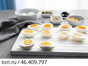 Hard-boiled cut eggs with ingredients on table. Стоковое фото, фотограф Pixel_shot / Фотобанк Лори