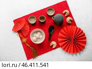 Mat with bowl of tangyuan, fortune cookies, teapot and Chinese decor on white background. Dongzhi Festival. Стоковое фото, фотограф Pixel_shot / Фотобанк Лори