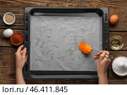 Woman greasing baking paper with oil on wooden background. Стоковое фото, фотограф Pixel_shot / Фотобанк Лори