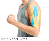 Sporty man with physio tape applied on arm against white background, closeup. Стоковое фото, фотограф Pixel_shot / Фотобанк Лори