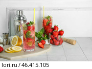 Glass of fresh strawberry mojito with shaker and jigger on white tile table. Стоковое фото, фотограф Pixel_shot / Фотобанк Лори