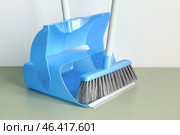 Blue dustpan and broom on floor near light wall, closeup. Стоковое фото, фотограф Pixel_shot / Фотобанк Лори