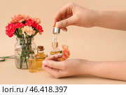 Female hands with bottle of cuticle oil and carnation flowers on color background, closeup. Стоковое фото, фотограф Pixel_shot / Фотобанк Лори