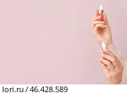 Female hands with bottles of cuticle oil on color background. Стоковое фото, фотограф Pixel_shot / Фотобанк Лори