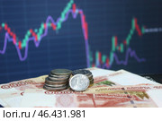 Купюры и монеты российского рубля на фоне графика торгов. Стоковое фото, фотограф Борис Килин / Фотобанк Лори