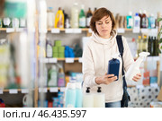 Store visitor woman purchases in household chemicals department, choose multisurface cleaner spray. Стоковое фото, фотограф Яков Филимонов / Фотобанк Лори