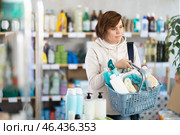 Woman with filled basket wanders around store, looking at display cases and inspects assortment. Стоковое фото, фотограф Яков Филимонов / Фотобанк Лори