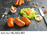 Вкусные колбаски гриль с соусом и картофелем на темном фоне. Стоковое фото, фотограф Pixel_shot / Фотобанк Лори