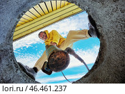 Bottom view of man immersing sewage pump into waste water of septic tank. Стоковое фото, фотограф Владимир Григорьев / Фотобанк Лори