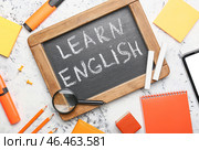 Классная доска с текстом УЧИТЬ АНГЛИЙСКИЙ и канцелярские принадлежности на светлом фоне. Стоковое фото, фотограф Pixel_shot / Фотобанк Лори