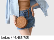 Молодая модница с сумочкой из ротанга на светлом фоне. Стоковое фото, фотограф Pixel_shot / Фотобанк Лори