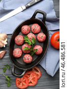 Форма для запекания с сырыми мясными шариками, овощами, ножом и салфеткой на темном деревянном фоне. Стоковое фото, фотограф Pixel_shot / Фотобанк Лори