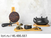 Стойки с сухим прессованным чаем пуэр, чайником, чашкой и ножом на светлом фоне. Стоковое фото, фотограф Pixel_shot / Фотобанк Лори
