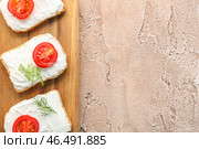 Деревянная доска из сухариков со сливочным сыром и помидорами на цветном фоне, крупным планом. Стоковое фото, фотограф Pixel_shot / Фотобанк Лори