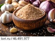 A wooden bowl filled with aromatic garlic salt - a mixture of sea salt and dried, crushed garlic. The coarse texture of the grains gives the mixture an appetizing appearance. Around the bowl are garlic heads and cloves in light purple husks, as well as scattered salt crystals. The background is done in warm, natural tones - the dark wooden covering emphasizes the rustic style and cozy culinary atmosphere. Стоковое AI-изображение, AI-художник Анна Кривицкая / Фотобанк Лори