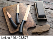 Доска с набором ножей и точильным камнем на деревянном фоне. Стоковое фото, фотограф Pixel_shot / Фотобанк Лори