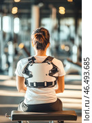 Young woman wearing posture corrector brace while sitting in gym. Стоковое AI-изображение, AI-художник Юрий Поздников / Фотобанк Лори