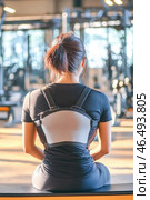 Young woman wearing posture corrector sitting in gym. Стоковое AI-изображение, AI-художник Юрий Поздников / Фотобанк Лори