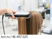 Женщина-парикмахер выпрямляет волосы клиента в салоне красоты, крупным планом. Стоковое фото, фотограф Pixel_shot / Фотобанк Лори