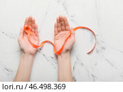 Женские руки с оранжевой лентой на светлом фоне. Концепция осведомленности о раковой лейкемии. Стоковое фото, фотограф Pixel_shot / Фотобанк Лори
