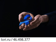 Человек с голубой лентой на темном фоне, крупным планом. Концепция рака толстой кишки. Стоковое фото, фотограф Pixel_shot / Фотобанк Лори