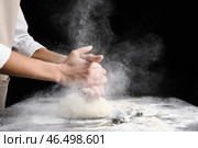 Женщина хлопает в ладоши и посыпает тесто мукой на темном фоне. Стоковое фото, фотограф Pixel_shot / Фотобанк Лори