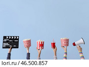 Множество рук с киношным щелчком, ведрами попкорна и мегафоном на голубом фоне. Стоковое фото, фотограф Pixel_shot / Фотобанк Лори