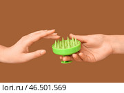 Женские руки с массажной щеткой для головы из силикона на коричневом фоне. Стоковое фото, фотограф Pixel_shot / Фотобанк Лори