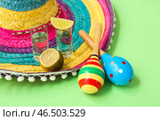 Сомбреро, маракасы и шоты текилы с лаймом на зеленом фоне, крупный план. Стоковое фото, фотограф Pixel_shot / Фотобанк Лори