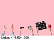 Множество рук с ведром попкорна, киношным хлопушкой и напитками на розовом фоне. Стоковое фото, фотограф Pixel_shot / Фотобанк Лори