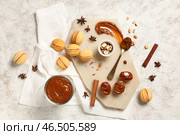 Доска с вкусным печеньем в форме ореха, варёной сгущёнкой и ингредиентами на белом шершавом столе. Стоковое фото, фотограф Pixel_shot / Фотобанк Лори