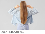Молодая женщина страдает от громкого шума на сером фоне, вид сзади. Стоковое фото, фотограф Pixel_shot / Фотобанк Лори