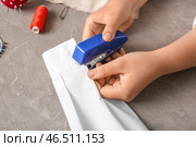 Женские руки с различными принадлежностями шьют блузку на гранжевом сером фоне. Стоковое фото, фотограф Pixel_shot / Фотобанк Лори