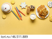 Композиция на Хануку с картофельными блинами, свечами, сметаной и крутилками на желтом столе. Стоковое фото, фотограф Pixel_shot / Фотобанк Лори