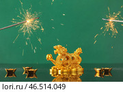 Золотая фигурка дракона, лодки с монетами и петардами на зеленом фоне. Празднование Нового года. Стоковое фото, фотограф Pixel_shot / Фотобанк Лори