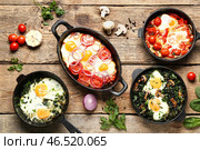 Форма для запекания и сковородки с вкусной шакшукой на деревянном фоне. Стоковое фото, фотограф Pixel_shot / Фотобанк Лори