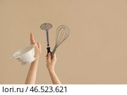 Женские руки, держащие дуршлаг, венчик и картофельную толкушку на коричневом фоне. Стоковое фото, фотограф Pixel_shot / Фотобанк Лори