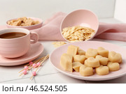 Тарелка с вкусными марципановыми конфетами, миндальными хлопьями и чашкой кофе на светлом кафельном столе. Стоковое фото, фотограф Pixel_shot / Фотобанк Лори