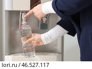Женщина наполняет пластиковую бутылку фильтрованной водой из охладителя в офисе. Стоковое фото, фотограф Pixel_shot / Фотобанк Лори