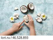 Женские руки с кокосовым маслом в миске и цветами плюмерии на голубом фоне. Стоковое фото, фотограф Pixel_shot / Фотобанк Лори