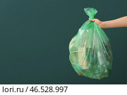 Женская рука держит полный мусорный мешок на зеленом фоне. Стоковое фото, фотограф Pixel_shot / Фотобанк Лори