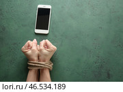 Женщина с связанными руками и мобильным телефоном на предпосылке цвета. Концепция наркомании. Стоковое фото, фотограф Pixel_shot / Фотобанк Лори