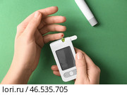 Уровень глюкозы женщины измеряя с цифровым глюкометром на предпосылке цвета. Контроль диабета. Стоковое фото, фотограф Pixel_shot / Фотобанк Лори