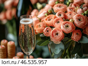 An elegant composition with a glass of sparkling champagne and a bouquet of lush flowers (ranunculus) in a delicate peach shade. The glass is filled with a bubbling drink, creating an atmosphere of celebration and luxury. In the background, bottle corks and a blurred silhouette of green glass are visible, hinting at the recent opening of a bottle of champagne.The flowers look fresh and airy, their soft petals create a feeling of tenderness and sophistication. The combination of golden shades of champagne, warm tones of flowers and a dark background gives the image an atmosphere of sophistication, coziness and romance. Стоковое AI-изображение, AI-художник Анна Кривицкая / Фотобанк Лори