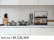 Белые кухонные столешницы с электрической плитой, кастрюлями и кухонными принадлежностями. Стоковое фото, фотограф Pixel_shot / Фотобанк Лори