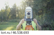 A surveyor with equipment works on a sunny day. Setting up and installing geodetic equipment in the working position. Implementation of a complex of geodetic works for engineering surveys. Стоковое видео, видеограф Скрипачев Антон / Фотобанк Лори